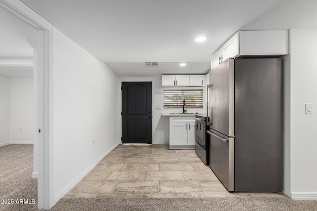 kitchen with visible vents, electric range oven, freestanding refrigerator, white cabinets, and a sink