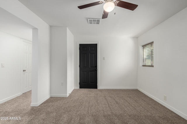 empty room with ceiling fan, carpet floors, visible vents, and baseboards