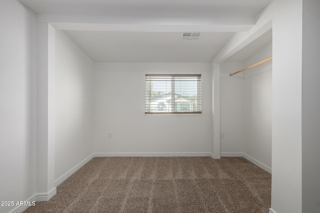 empty room with carpet floors, visible vents, lofted ceiling with beams, and baseboards