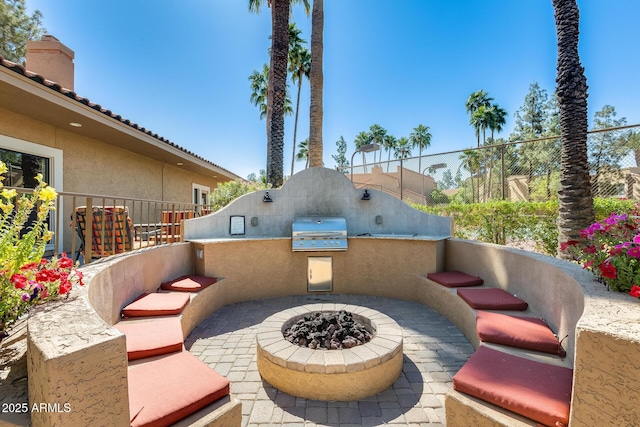 view of patio / terrace with an outdoor kitchen, grilling area, a fire pit, and fence