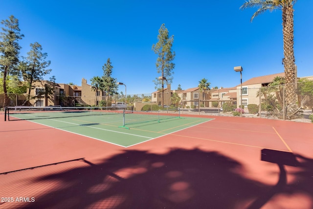 view of tennis court featuring fence, community basketball court, and a residential view