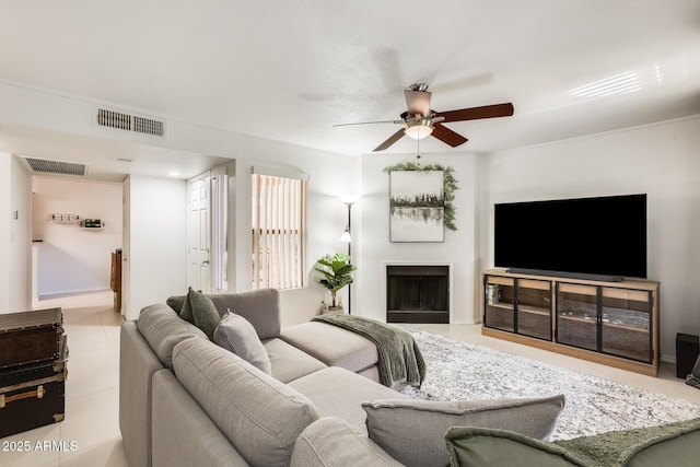 tiled living room featuring a ceiling fan, visible vents, and a fireplace