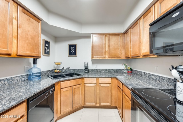 kitchen with a sink, dark stone countertops, black appliances, brown cabinetry, and light tile patterned floors