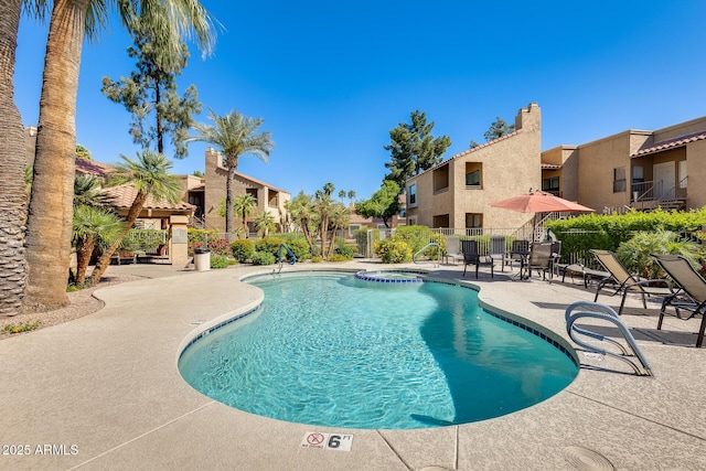 view of swimming pool featuring a residential view, a patio area, a pool with connected hot tub, and fence