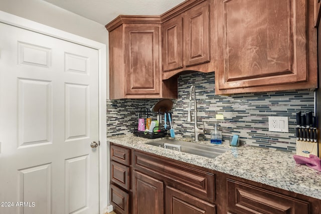 kitchen with light stone counters, sink, and decorative backsplash