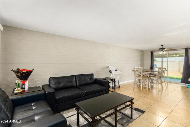 living room featuring brick wall, light tile patterned floors, and ceiling fan