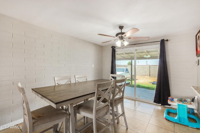 dining space featuring brick wall, light tile patterned floors, and ceiling fan