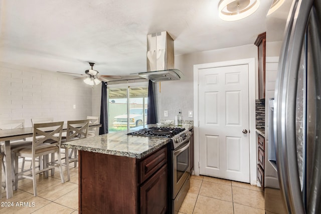 kitchen featuring light tile patterned floors, appliances with stainless steel finishes, light stone counters, island exhaust hood, and ceiling fan