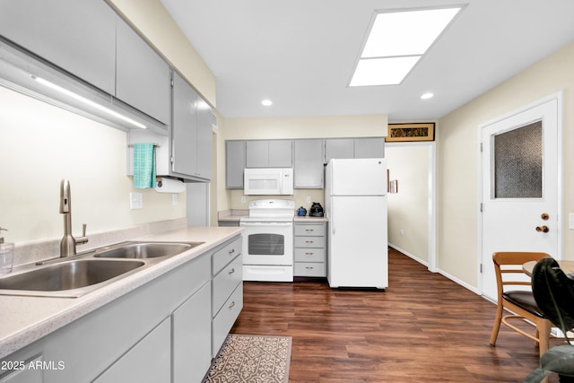 kitchen featuring sink, white appliances, gray cabinets, a skylight, and dark hardwood / wood-style flooring