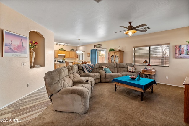 living room featuring a wealth of natural light, visible vents, rail lighting, and a ceiling fan