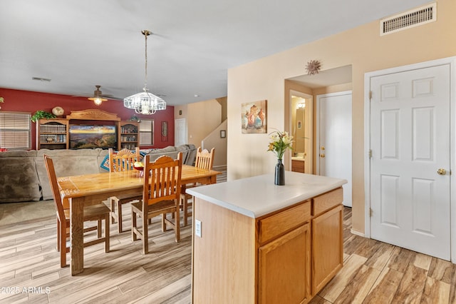 dining area with visible vents, light wood-style flooring, and ceiling fan with notable chandelier