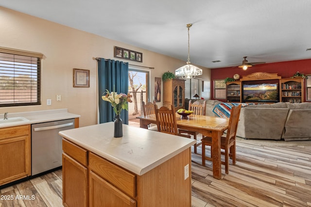 kitchen featuring light countertops, light wood-style floors, stainless steel dishwasher, ceiling fan with notable chandelier, and open floor plan