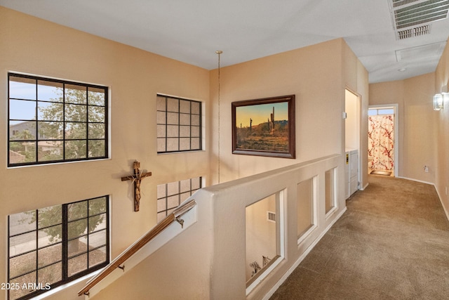 hallway with carpet flooring, an upstairs landing, and visible vents