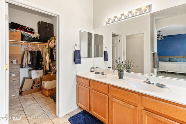 ensuite bathroom with double vanity, ensuite bath, a ceiling fan, and a sink