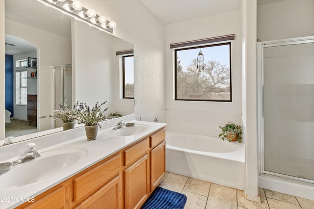 bathroom featuring double vanity, a bath, a stall shower, and a sink