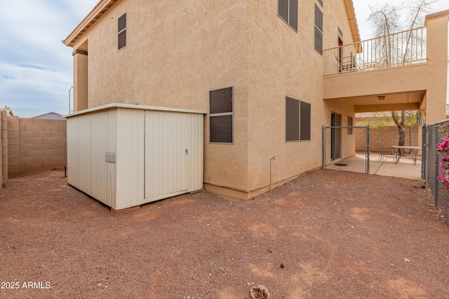 back of house featuring stucco siding, an outbuilding, a storage shed, and a patio area