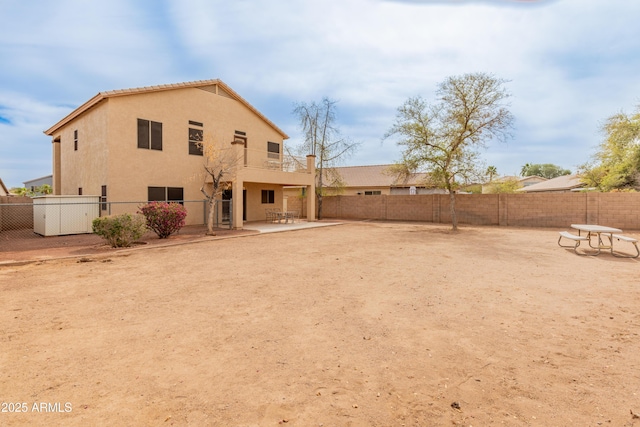 rear view of house with stucco siding, a patio, and a fenced backyard