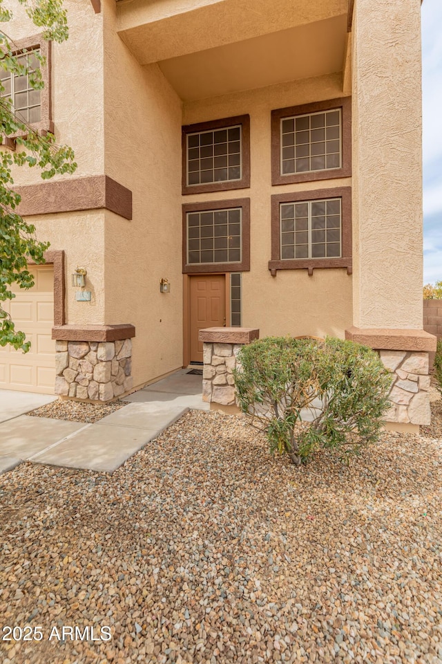 doorway to property with stone siding and stucco siding