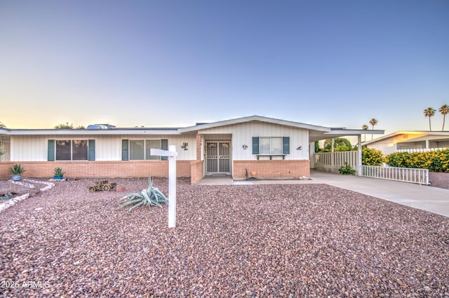10620 W Clair Dr, Sun City, AZ 85351 - view of front facade featuring brick siding, fence, driveway, an attached carport, and board and batten siding