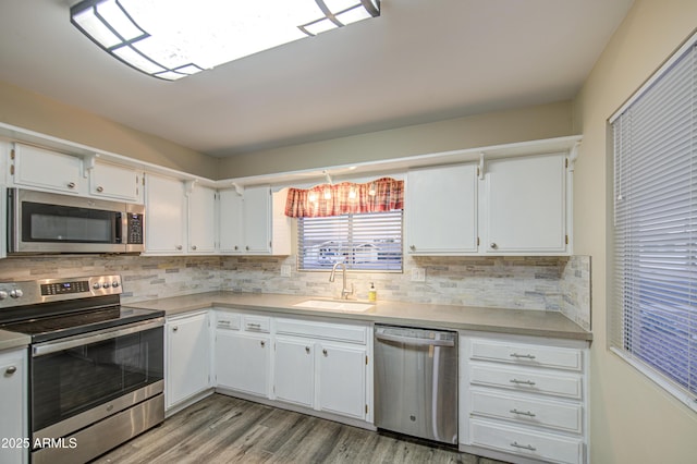 10620 W Clair Dr, Sun City, AZ 85351 - kitchen featuring appliances with stainless steel finishes, a sink, light wood-type flooring, white cabinetry, and decorative backsplash