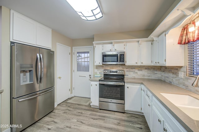 10620 W Clair Dr, Sun City, AZ 85351 - kitchen with stainless steel appliances, a sink, light wood-type flooring, decorative backsplash, and plenty of natural light
