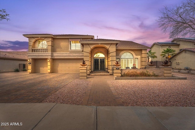 mediterranean / spanish-style house featuring decorative driveway, an attached garage, and stucco siding