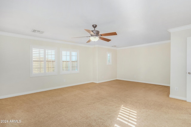 unfurnished room featuring ceiling fan, plenty of natural light, light colored carpet, and ornamental molding