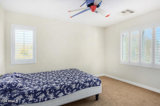 bedroom featuring multiple windows, ceiling fan, and carpet