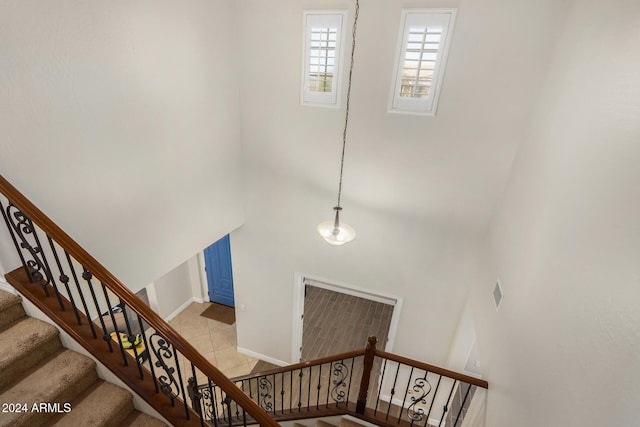 stairway featuring tile patterned flooring and a towering ceiling