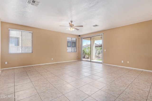 tiled empty room featuring a textured ceiling, plenty of natural light, and ceiling fan