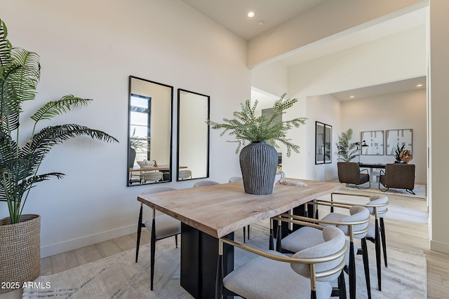 dining area with light wood-type flooring and a high ceiling