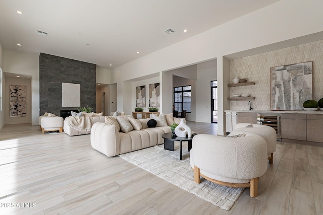 living room featuring sink, light hardwood / wood-style floors, and beverage cooler