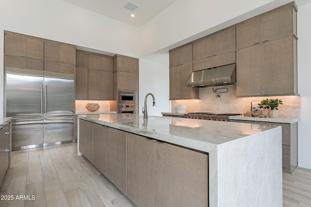 kitchen with stainless steel appliances, a spacious island, ventilation hood, sink, and backsplash