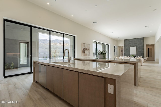 kitchen with sink, plenty of natural light, light stone counters, and a spacious island