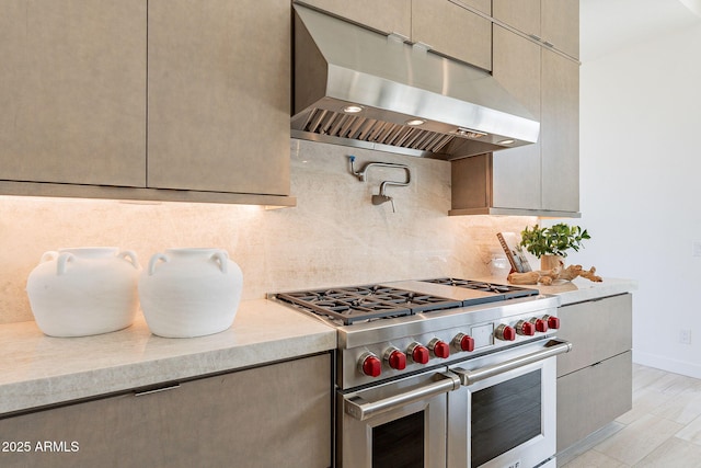 kitchen featuring light wood-type flooring, range with two ovens, extractor fan, and backsplash