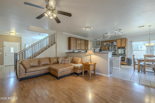 living room featuring crown molding, ceiling fan with notable chandelier, light hardwood / wood-style floors, and a textured ceiling