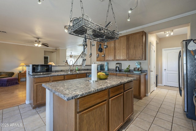 kitchen featuring crown molding, light tile patterned flooring, a center island, and appliances with stainless steel finishes