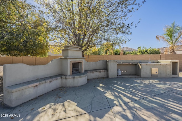 view of patio with exterior kitchen and an outdoor fireplace