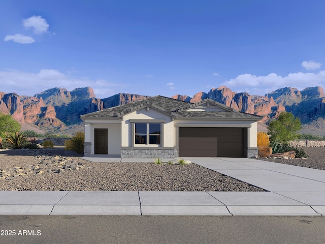 view of front of home featuring stucco siding, concrete driveway, a mountain view, a garage, and stone siding