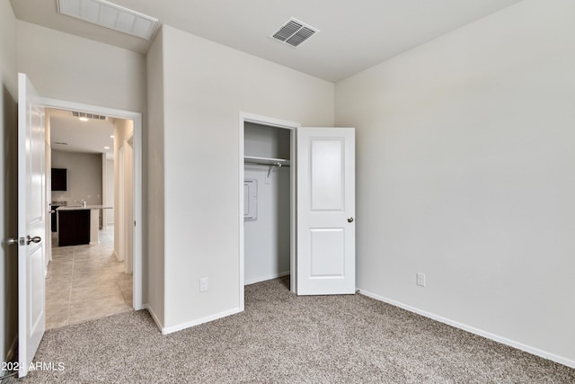 unfurnished bedroom featuring baseboards, a closet, visible vents, and light colored carpet