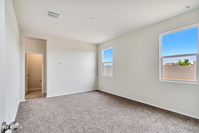 empty room featuring carpet floors, visible vents, and baseboards