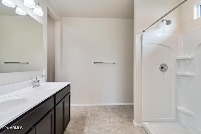 full bathroom with double vanity, baseboards, walk in shower, and a sink