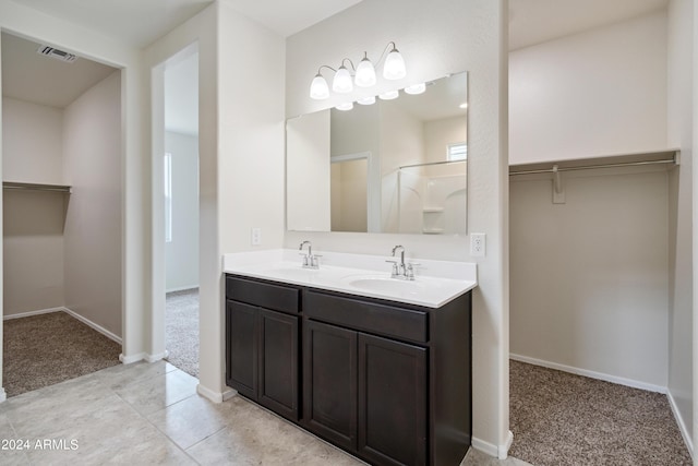 bathroom with a spacious closet, double vanity, a sink, and visible vents