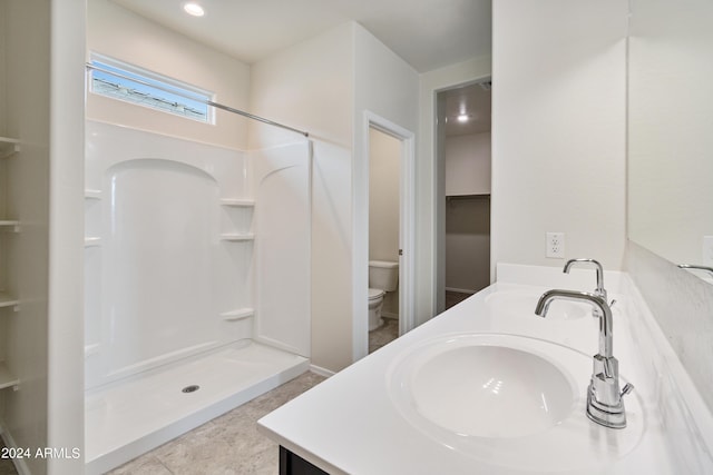 full bath featuring double vanity, a stall shower, a sink, and toilet