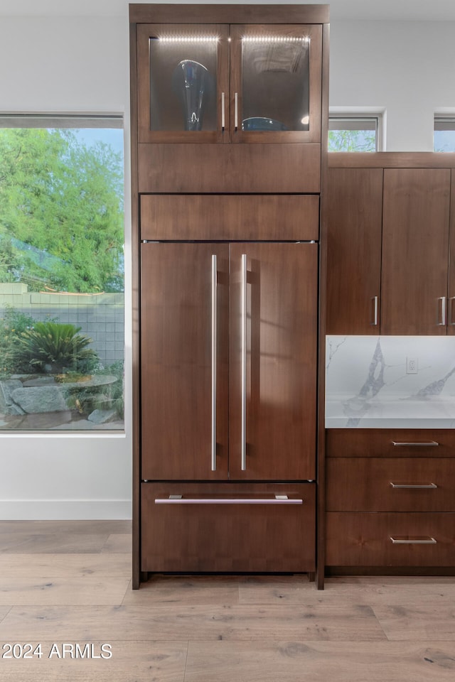 details featuring paneled refrigerator, light stone countertops, and light wood-type flooring