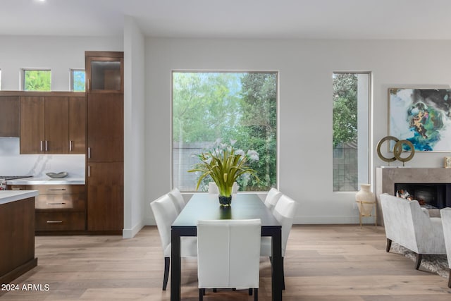 dining area featuring a high end fireplace, light hardwood / wood-style flooring, and a healthy amount of sunlight