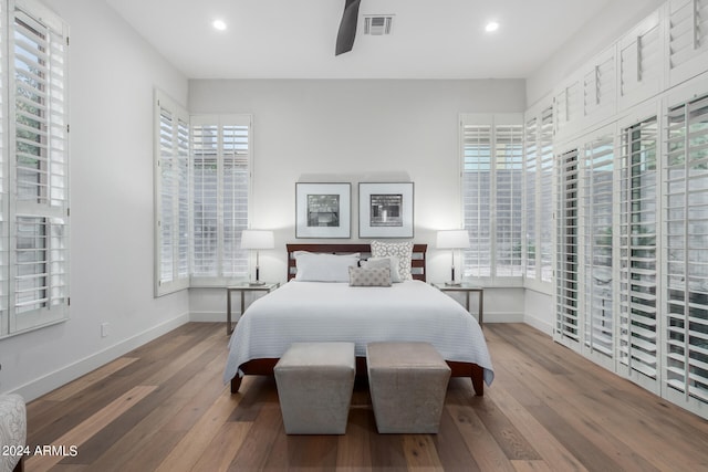 bedroom featuring ceiling fan, multiple windows, and hardwood / wood-style floors