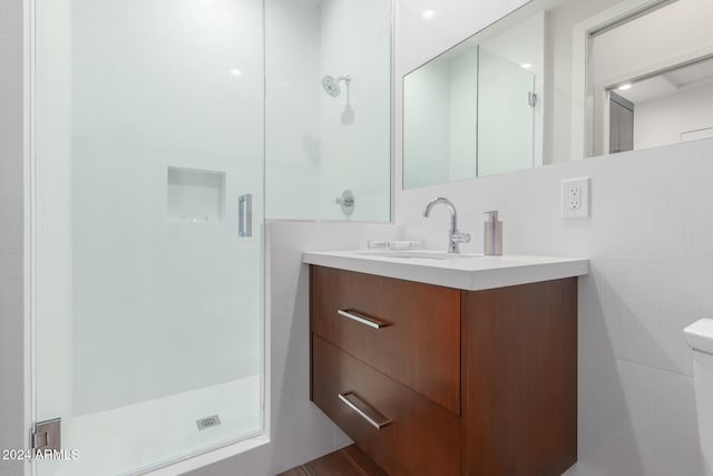 bathroom with hardwood / wood-style flooring, toilet, vanity, tile walls, and an enclosed shower