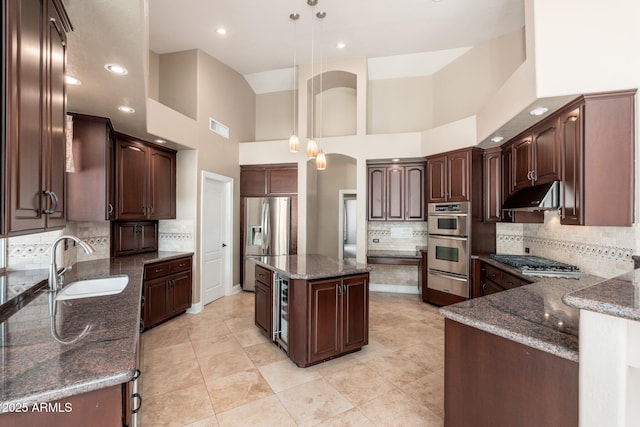 12120 E Cortez Dr, Scottsdale, AZ 85259 - kitchen with appliances with stainless steel finishes, under cabinet range hood, a warming drawer, decorative backsplash, and a towering ceiling