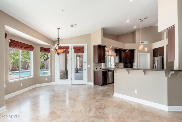 12120 E Cortez Dr, Scottsdale, AZ 85259 - kitchen with vaulted ceiling, appliances with stainless steel finishes, a kitchen bar, stone counters, and dark brown cabinets